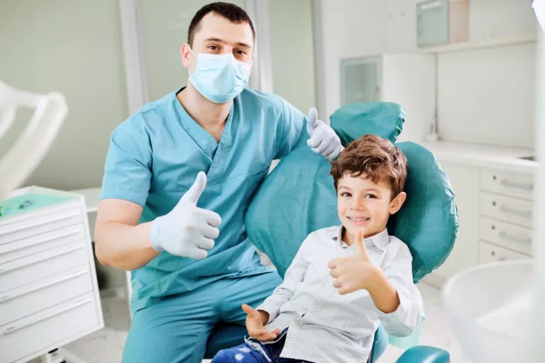 歯科医師と少年が笑顔でグッドポーズ