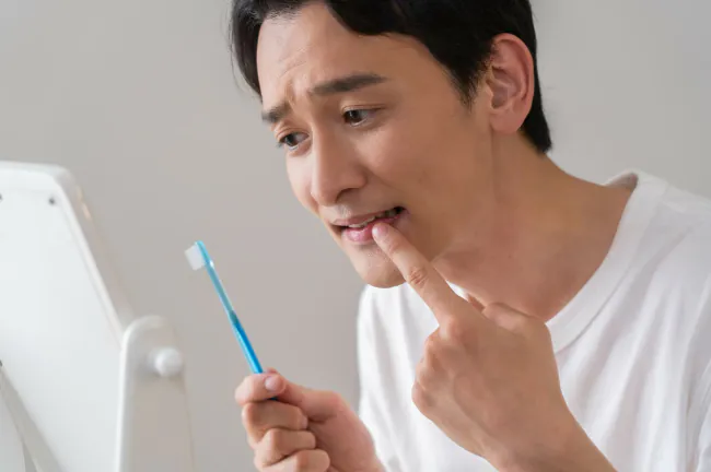 歯磨き中に歯周病が気になり歯ぐきを確認する男性