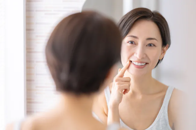 インプラント治療を受け鏡をチェックする女性
