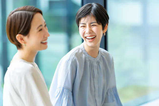 審美歯科で歯が美しく整い笑顔で同僚と会話する女性