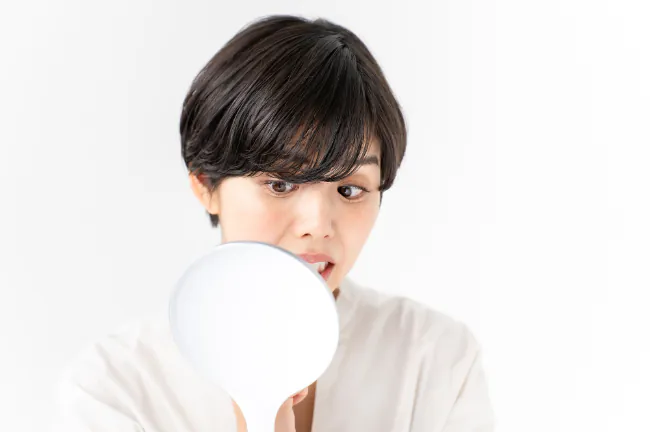 鏡を見て歯を気にする女性