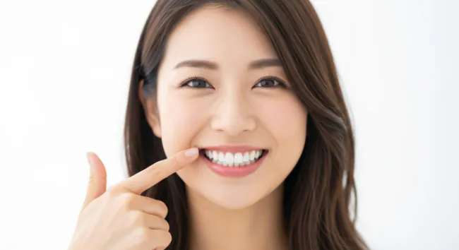 根管治療をした歯を指さして笑顔を見せる女性