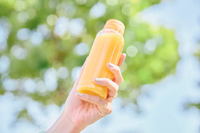 ジュースの入ったボトルを持つ手